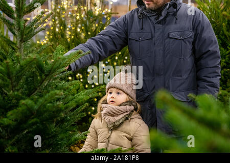 Father and daughter choose a Christmas tree in a shop Stock Photo