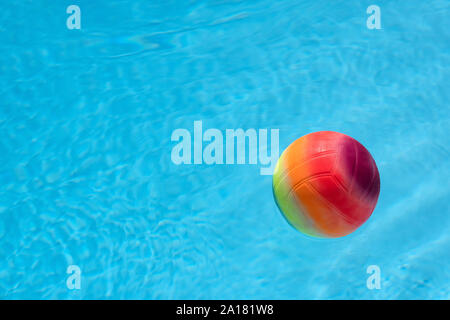 Multi-coloured ball floating on a swimming pool surface Stock Photo