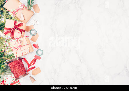 Craft boxes and wraps packed as Christmas gifts and red ribbons on white marble background. Holiday season concept. Horizontal Stock Photo