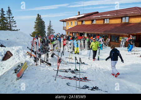 Poiana Brasov, Romania - February 20, 2019: Julius Romer Hutte / Postavaru hut with skiers and snowboarders moving around on the outside terrace. Stock Photo