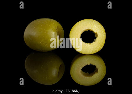 Group of one whole one slice of pitted green olive isolated on black glass Stock Photo