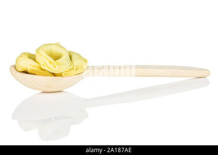 Group of four whole fresh yellow spinach filled tortelloni in a wooden spoon isolated on white background Stock Photo