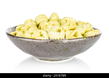 Lot of whole fresh yellow spinach filled tortelloni in dark ceramic bowl isolated on white background Stock Photo