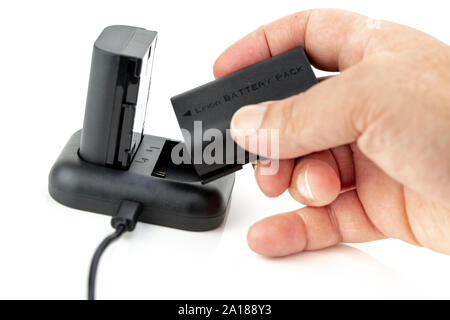 Man manipulating Camera battery and charger on white background Stock Photo