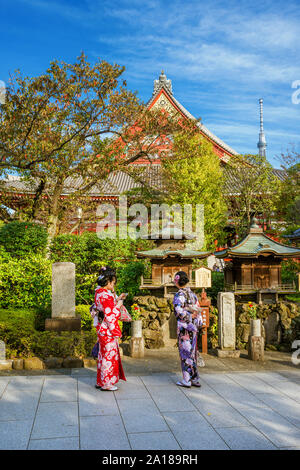 Tokyo between tradition and modernity. Young japanese girls wearing kimons and holding mobile hones in old Asakusa Temple area with the new Skytree to Stock Photo