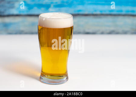 Pint of beer on a white table with a colourful wooden wall Stock Photo