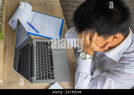 Overworked businessman having headache while working on laptop Stock Photo