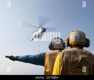 190912-N-IQ884-1239  RED SEA (Sept. 12, 2019) Aviation Boatswain’s Mate (Handling) 1st Class Joseph Martinez, assigned to amphibious assault ship USS Boxer (LHD 4), signals a Military Sealift Command SA-330J Puma helicopter with Aviation Boatswain’s Mate (Handling) Airman Johnny Snowden, also assigned to Boxer, on the flight deck during a vertical replenishment-at-sea. Boxer is part of the Boxer Amphibious Ready Group and 11th Marine Expeditionary Unit and is deployed to the U.S. 5th Fleet area of operations in support of naval operations to ensure maritime stability and security in the Centra Stock Photo