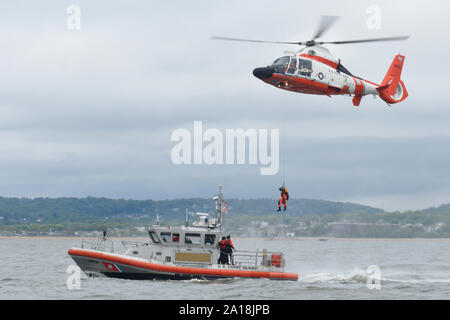 A Coast Guard MH-65 Dolphin helicopter hoists a rescue swimmer from the deck of a Coast Guard 45-foot Response Boat-medium near Brooklyn, New York, May 14, 2019. The aircrew from Air Station Atlantic City regularly trains with members from Station New York to ensure Coast Guard men and women are ready to respond when called upon. (U.S. Coast Guard photo by Petty Officer 2nd Class Steve Strohmaier) Stock Photo