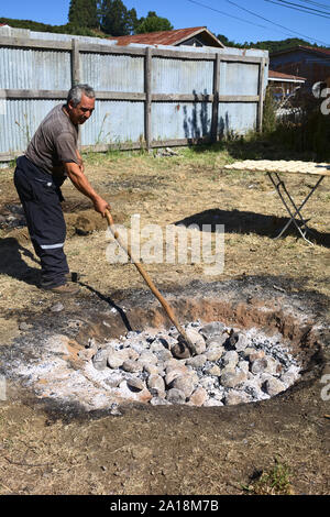 ACHAO, CHILE - FEBRUARY 6, 2016: Unidentified man preparing the hole with hot stones in which the traditional Chilotan dish Curanto al hoyo is cooked Stock Photo