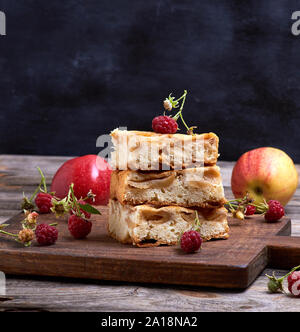 square pieces of apple pie are stacked on a brown wooden board, sponge cake Stock Photo