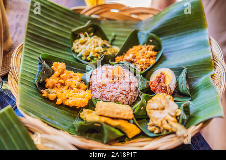 Nasi lemak, Nasi campur, Indonesian Balinese rice with potato fritter, sate lilit, fried tofu, spicy boiled eggs, and peanut Stock Photo