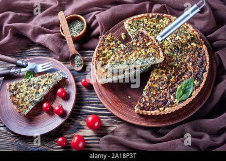 spring onions, heavy cream, eggs, cheese tart on an earthenware plates on a rustic wooden table with brown cloth, horizontal view from above Stock Photo