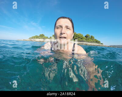 Mature woman swimming in clear blue Adriatic sea Stock Photo