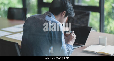 Hard-working male UI web designer working on his new smartphone templates project while using laptop computer Stock Photo