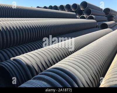 stacked-black-corrugated-plastic-drainage-pipes-partially-wrapped-in