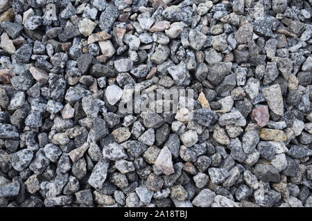 Gravel Rock Texture. Crushed stone and gravel on the ground. Texture background brown stones on a black earth background. Image of broken stones and g Stock Photo