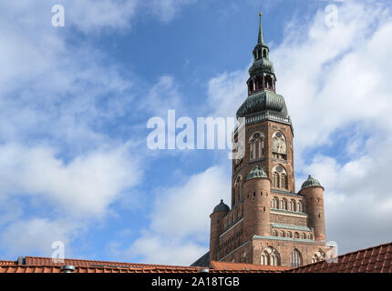Tower of the St Nikolas church, cathedral of Greifswald over the roofs against a blue sky with clouds, copy space Stock Photo