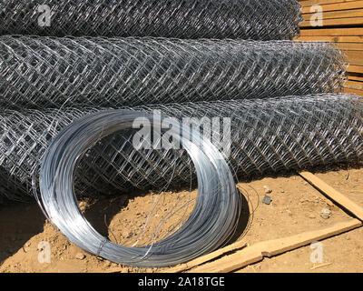 Metal mesh netting rolled into rolls and coils of steel wire. Rolled chain-link fence. Stock Photo