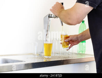 Man is drawing beer in glasses from a simple tap at an open air festival, copy space, selected focus, narrow depth of field Stock Photo