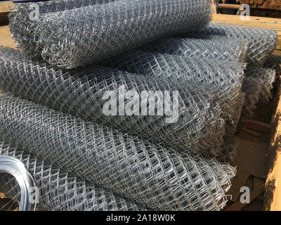 Metal mesh netting rolled into rolls and coils of steel wire. Rolled chain-link fence. Stock Photo