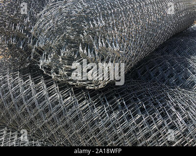 Rolled chain-link fence. Metal mesh netting rolled into rolls. Stock Photo