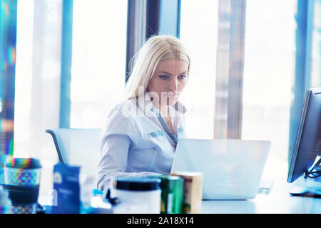 Side view portrait of businesswoman using computer at office desk Stock Photo