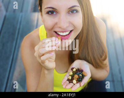 Fitness healthy woman eating mix of nuts seeds dried fruit outdoor. Stock Photo