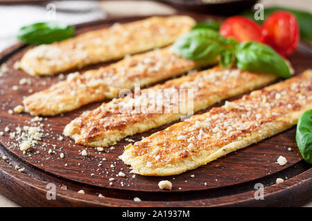 Vegan breadsticks with garlic and cashew cheese served with tomatoes and basil on wooden cutting board Stock Photo