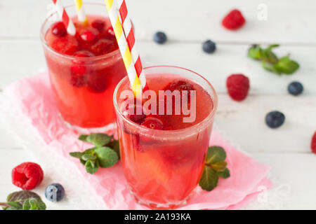 Fresh pink lemonade with raspberry, cranberry, strawberry, apple, lime decorated with mint leaves on white rustic table Stock Photo