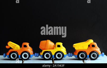 Line of three toy trucks over black background Stock Photo