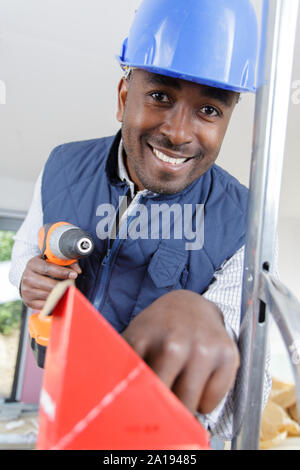 builder with cordless power tool reaching for screws Stock Photo