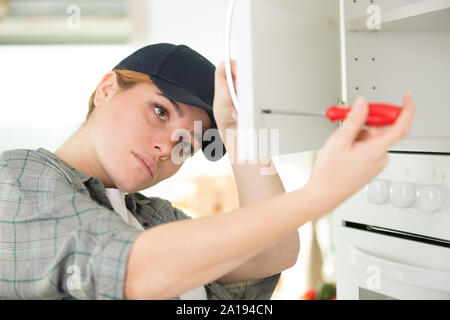 woman using a screw driver while installing a cabinet Stock Photo
