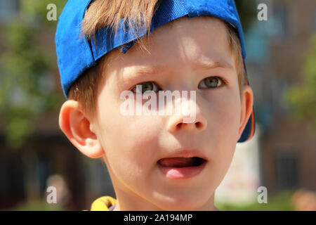 Close up portrait of a boy with serious face expression wearing blue baseball cap Stock Photo