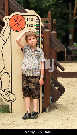 Five year old boy measuring his height on the children playground Stock Photo