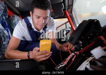 mechanic checking voltage of car battery in car service centre Stock Photo
