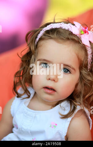 Portrait of a sweet one year old girl  against blurred bright colorful background Stock Photo