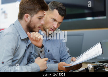 two men reading and discussing papers Stock Photo