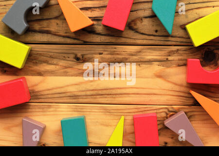Flat lay of bright colorful wooden figures scattered on wooden light brown planks, abstract background Stock Photo