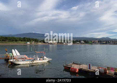 moored boat and pier near Iho Tewoo Beach on Jeju island with scenic cloudscape and Hallasan mountain on background Stock Photo