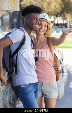 portrait of a happy couple pointing away on summer vacation Stock Photo