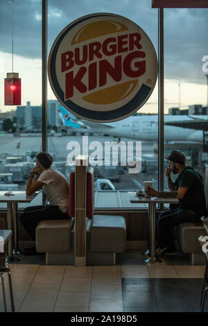 Burger King, people sit eating inside fast food outlet overlooking Barajas Airport, Madrid, Spain, Europe Stock Photo