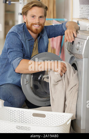 young man putting laundry in washing machine Stock Photo