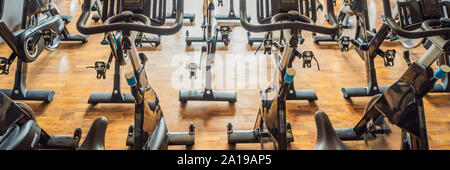 Aerobics spinning exercise bikes gym room with many in a row BANNER, LONG FORMAT Stock Photo