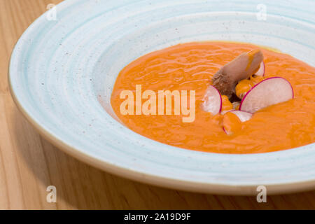 Fresh salmorejo (cold tomato soup) with tuna filet and garnish served in a white bowl, a traditional delicacy in Andalusia, Spain. Stock Photo