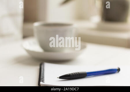 a clean notebook with a pen and a coffee Cup on the table by the window Stock Photo