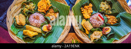 Nasi lemak, Nasi campur, Indonesian Balinese rice with potato fritter, sate lilit, fried tofu, spicy boiled eggs, and peanut BANNER, LONG FORMAT Stock Photo