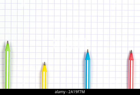 Multicolored striped pencils on white squared paper notebook background. Top view Stock Photo
