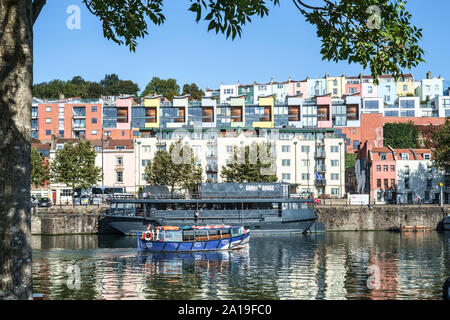 Seen along the Harbourside in Bristol UK. Grain Barge is a floating Pub, one of the Guardian Papers top 50 with the colourful houses of Clifton Wood Stock Photo