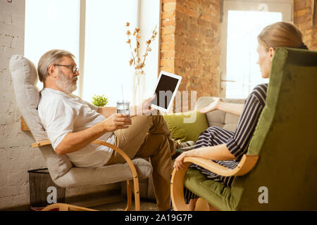 Senior man working with tablet at home - concept of home studying. Caucasian male model doing his homework with teacher while serfing in internet, watching cinema or webinar, online lessons. Stock Photo